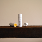 Vely Lip Balms on a wooden surface with a neutral background