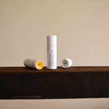 Vely Lip Balms on a wooden surface with a neutral background