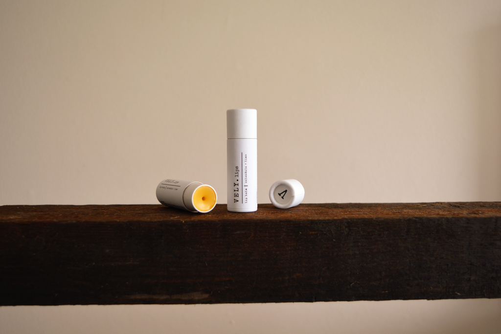 Vely Lip Balms on a wooden surface with a neutral background