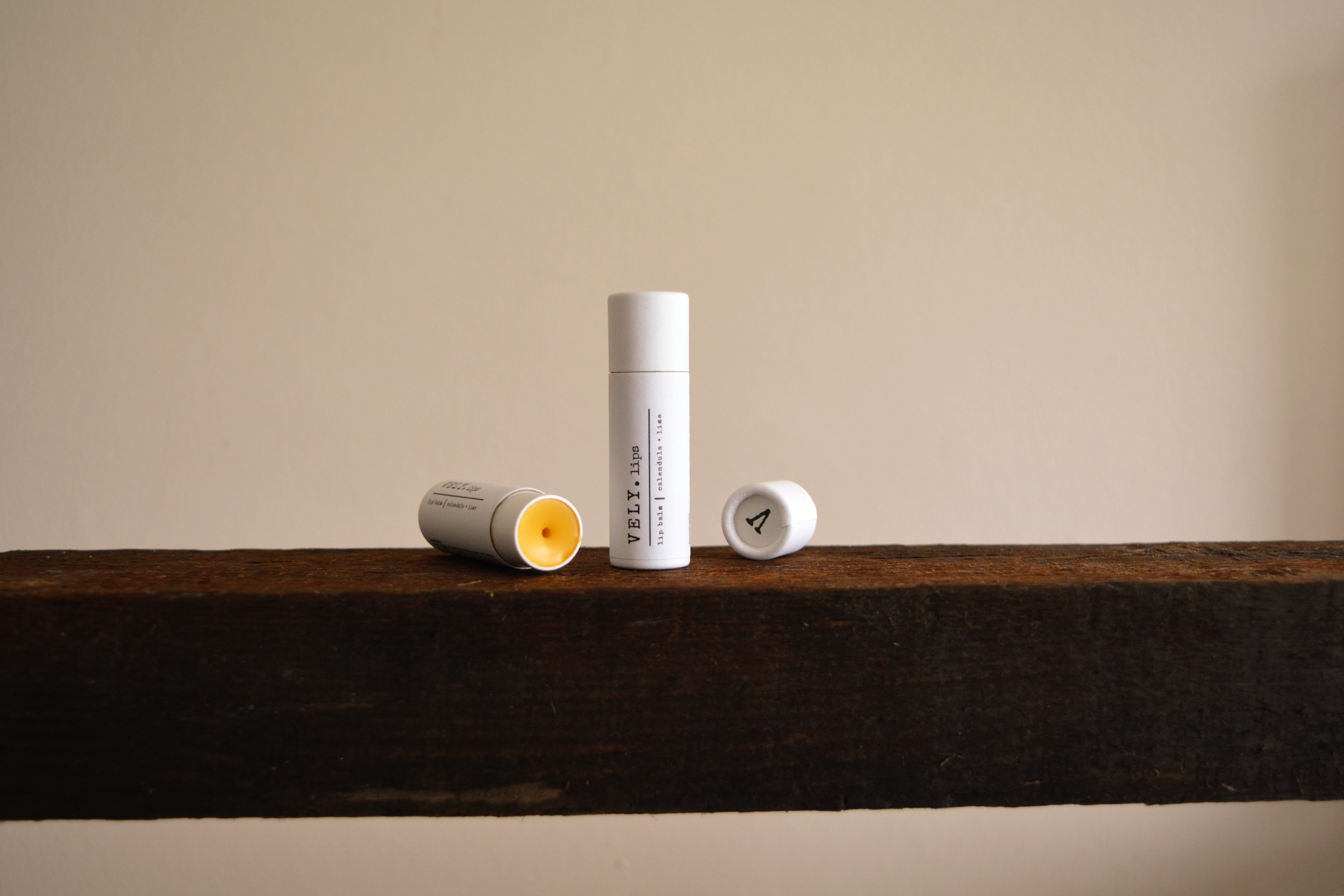 Vely Lip Balms on a wooden surface with a neutral background