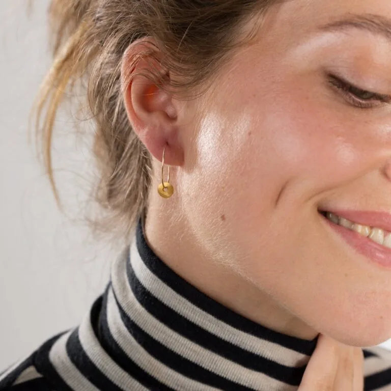 a woman wearing gold hoop earrings