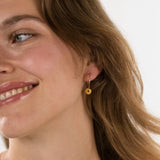 a woman wearing gold hoop earrings on a white background