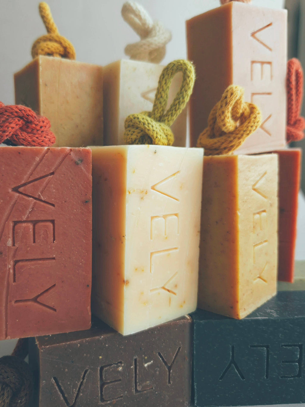 Assorted bars of soap with 'VELY' branding on a neutral background