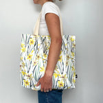 Person holding a Bianca Williams tote bag with daffodil design against a plain background
