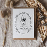 Mother's Day Greeting card with floral design and text. Printed on seed paper. Placed on a textured surface with dried plants and scissors.