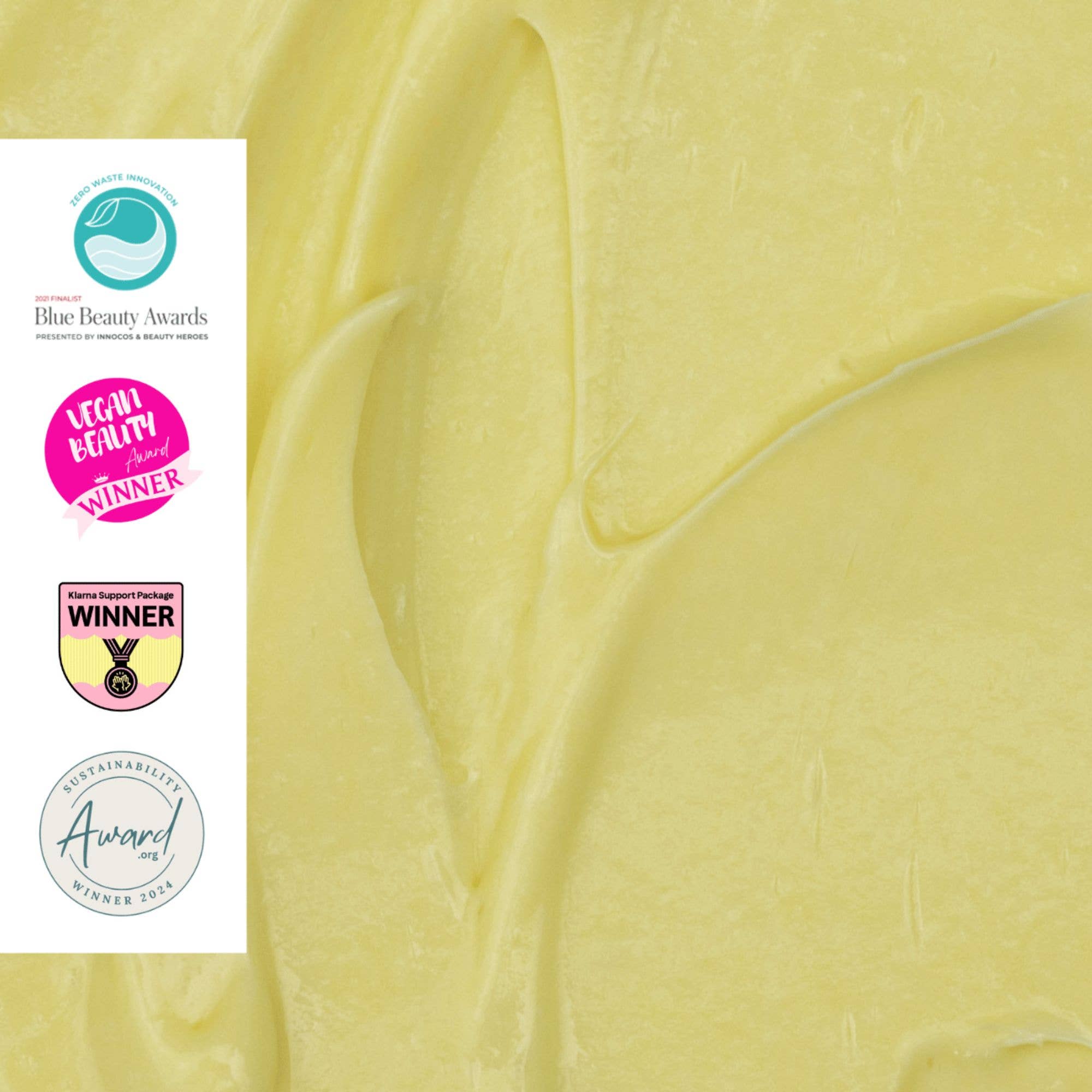 Close-up of yellow cream with Blue Beauty Awards, L'Occitane Healthy Winner, and Sustainability Award logos.