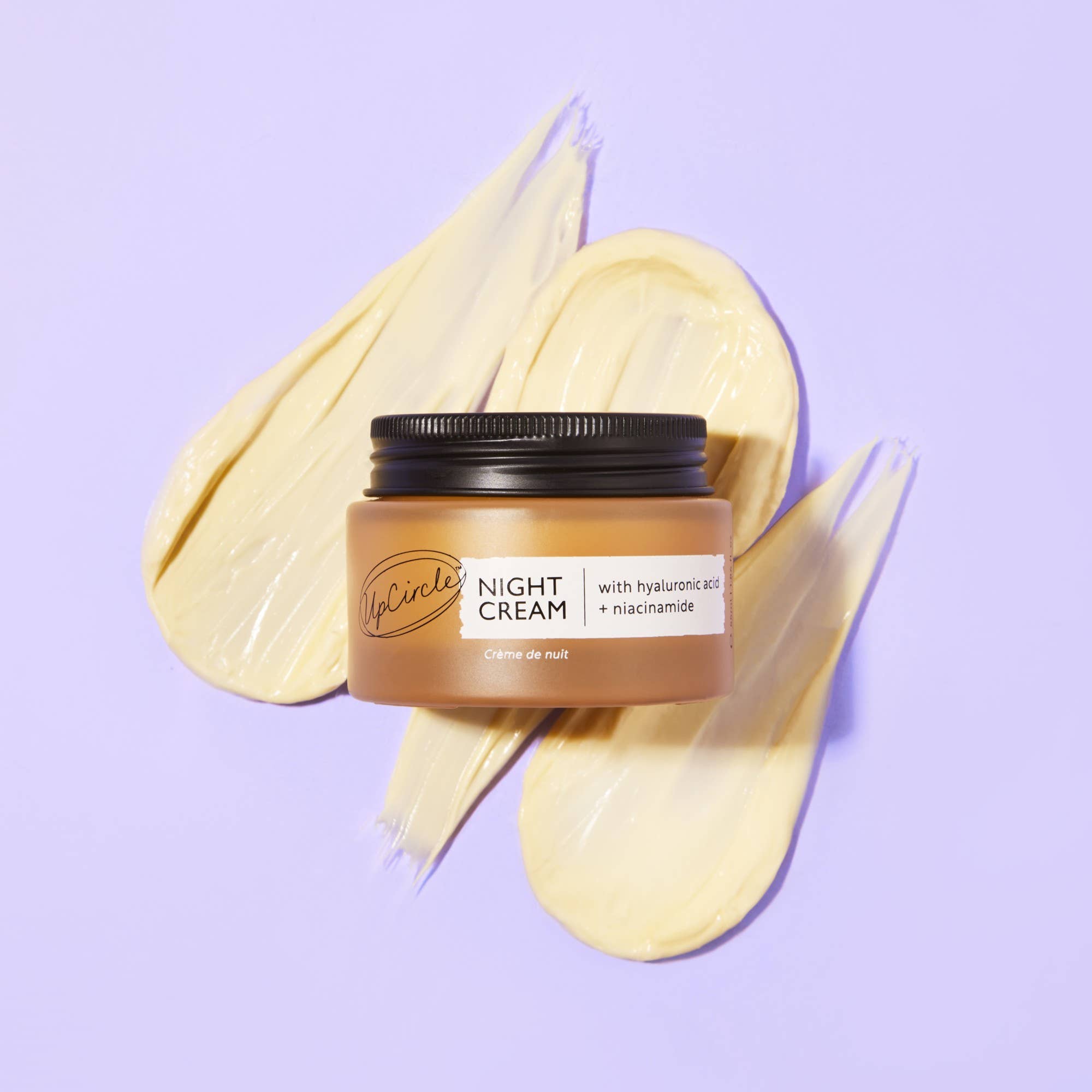 Jar of UpCircle Night Cream with decorative spread cream on a light purple background