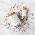 Two 'Salt & Steam Beauty Sleep' products on a textured surface with colorful bath salts.