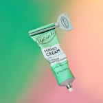 Green tube of Upcircle hand cream with a grey tube squeezer on a colorful gradient background