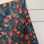 Hanging teatowel with red floral poppy pattern on a dark background draped over a white surface.