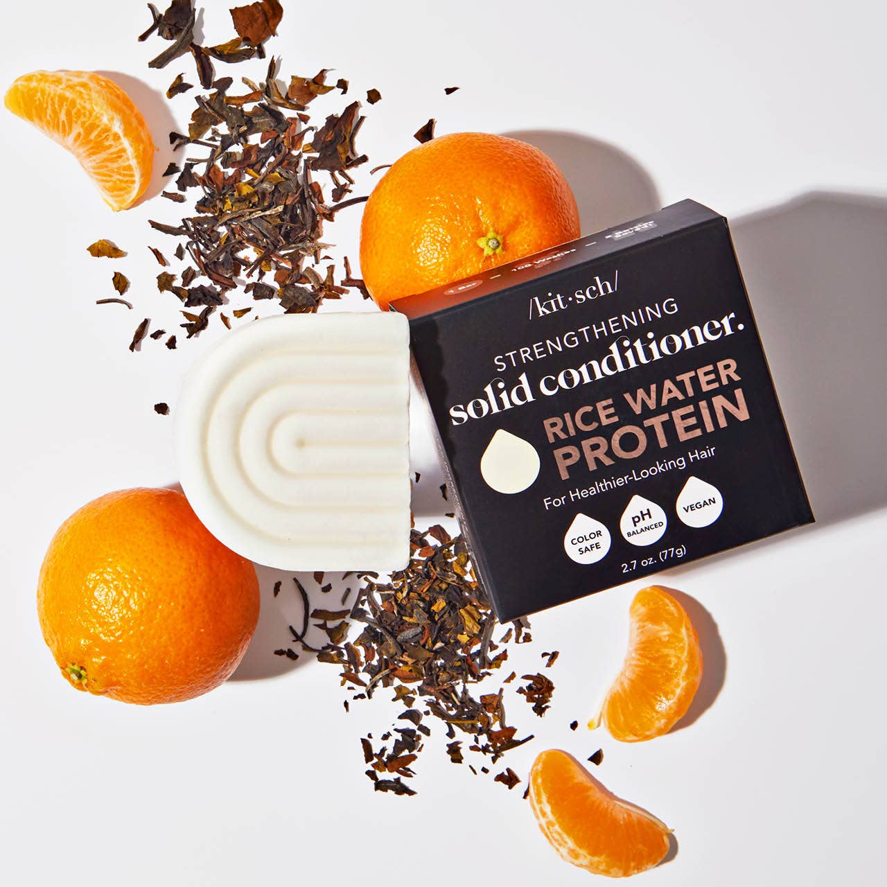 Kitsch solid conditioner bar with rice water protein, oranges, and tea leaves on a white background