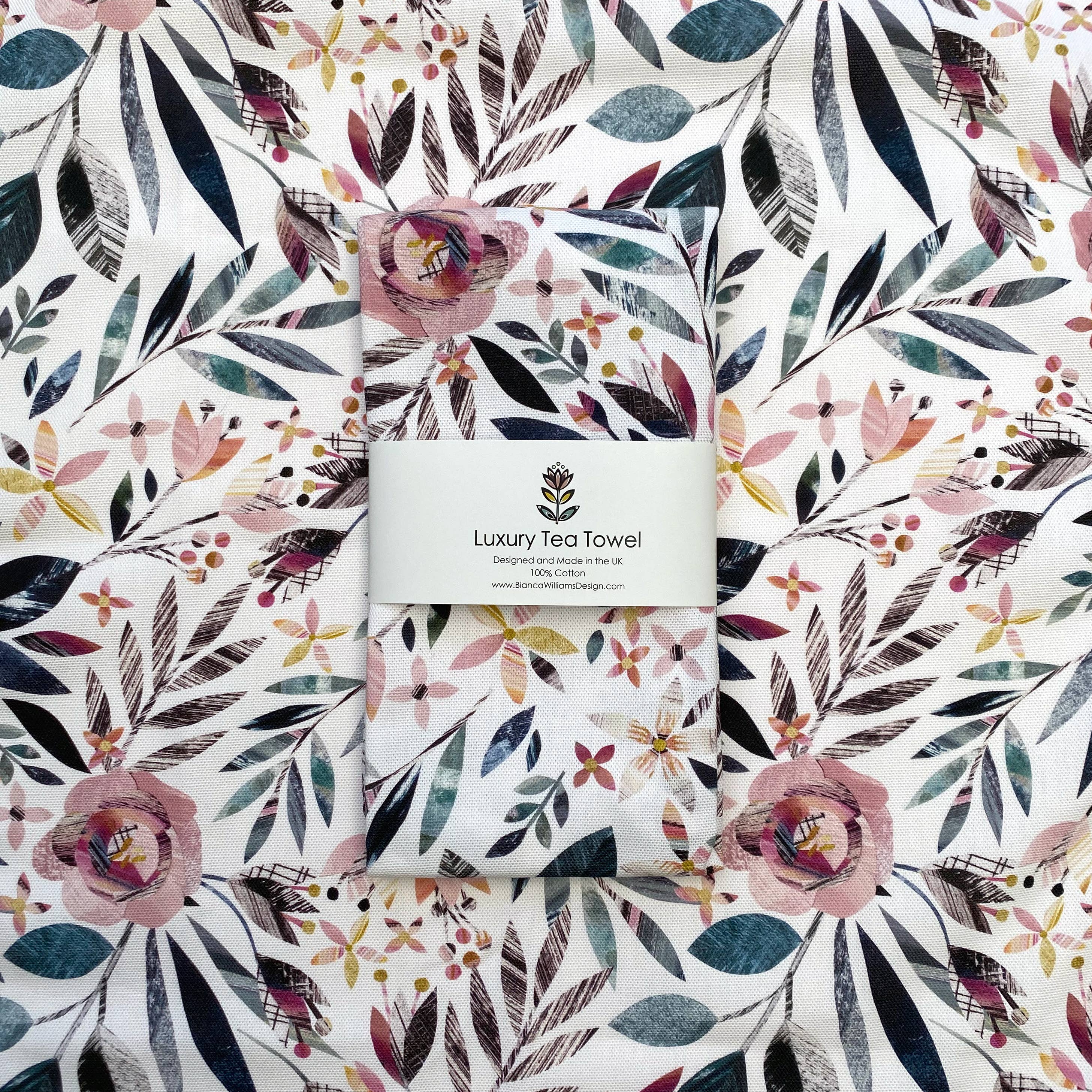 Set of pink floral patterned tea towels with a visible brand label on a matching floral background.