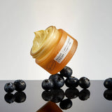 Jar of UpCircle Night Cream with blueberries on a reflective surface