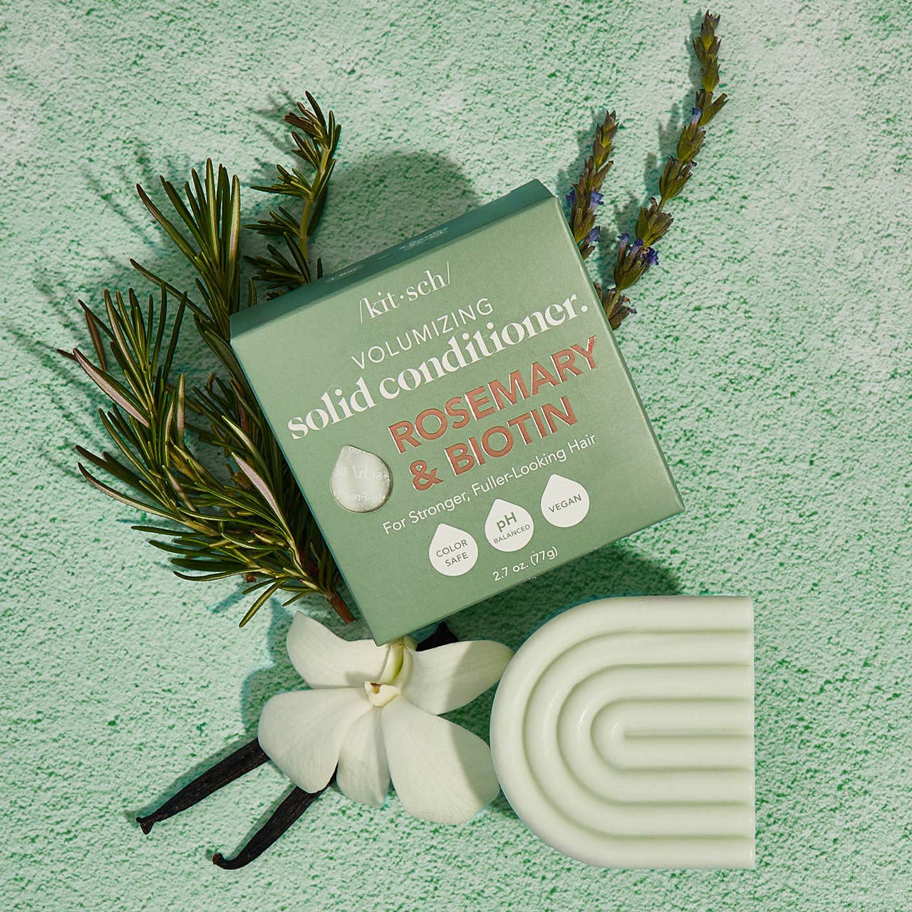 Kitsch Volumising Solid Conditioner packaging with rosemary and biotin on a green textured background
