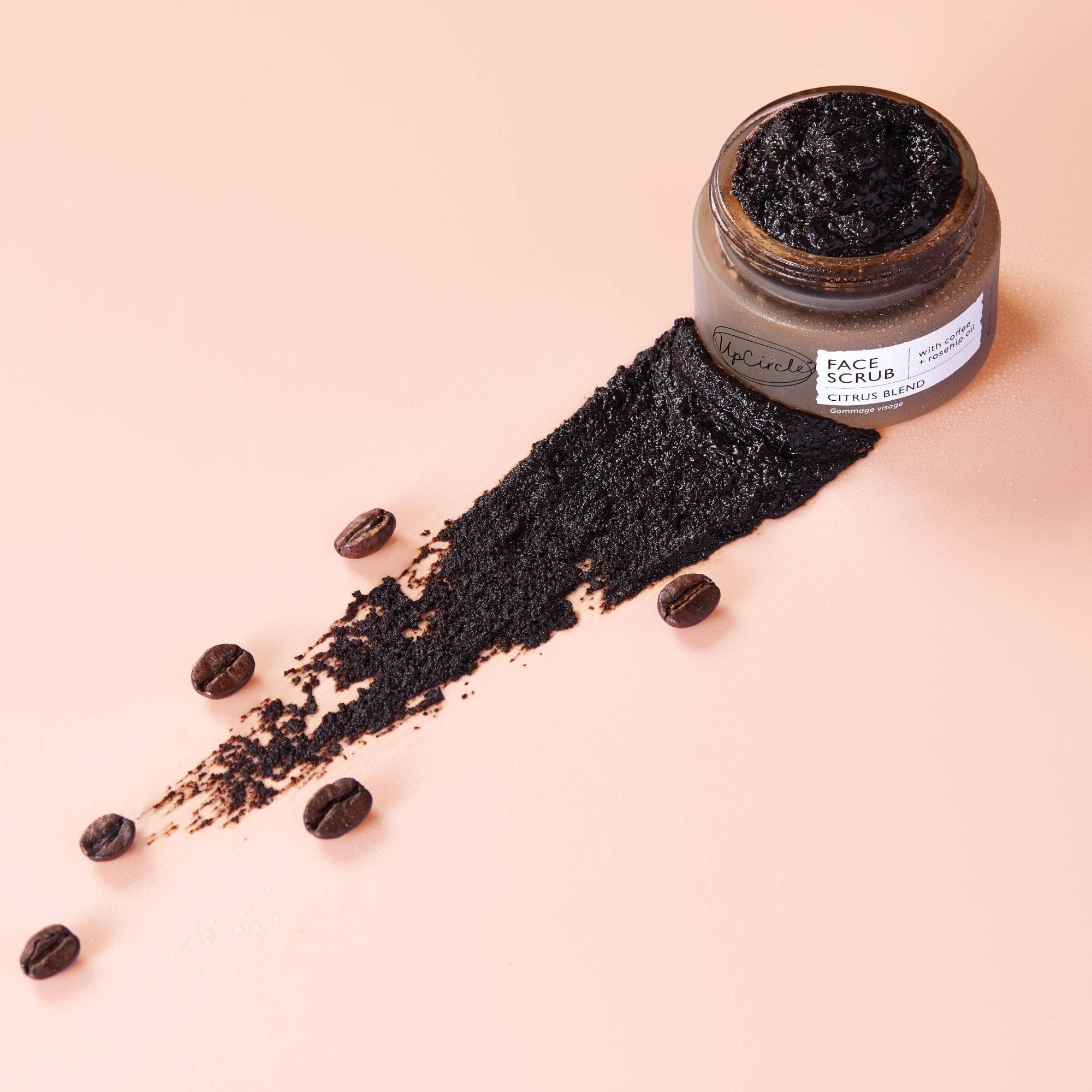 Jar of face scrub with coffee beans on a pink background