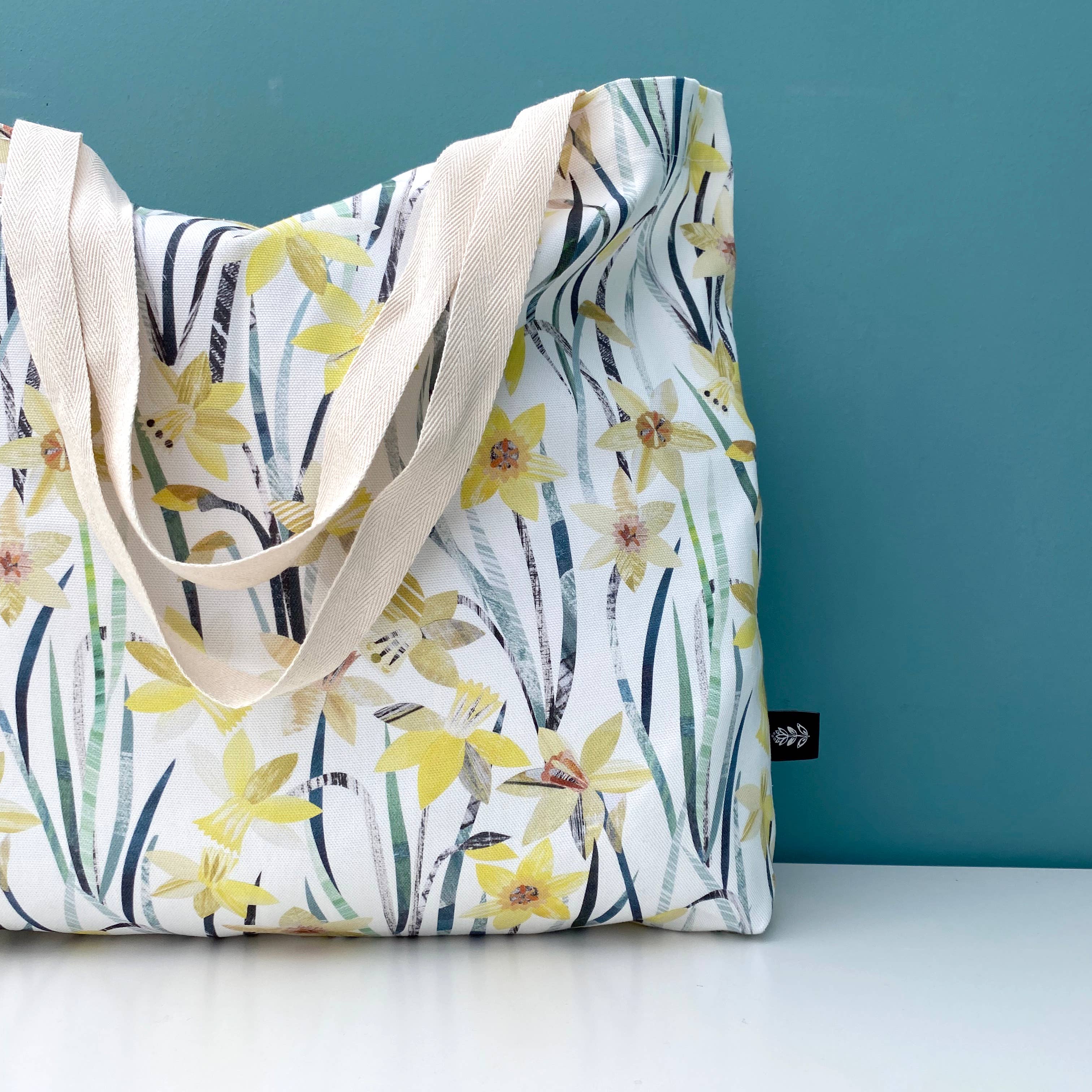 Bianca Williams Daffodil Floral tote bag with yellow flowers and green leaves on a white background