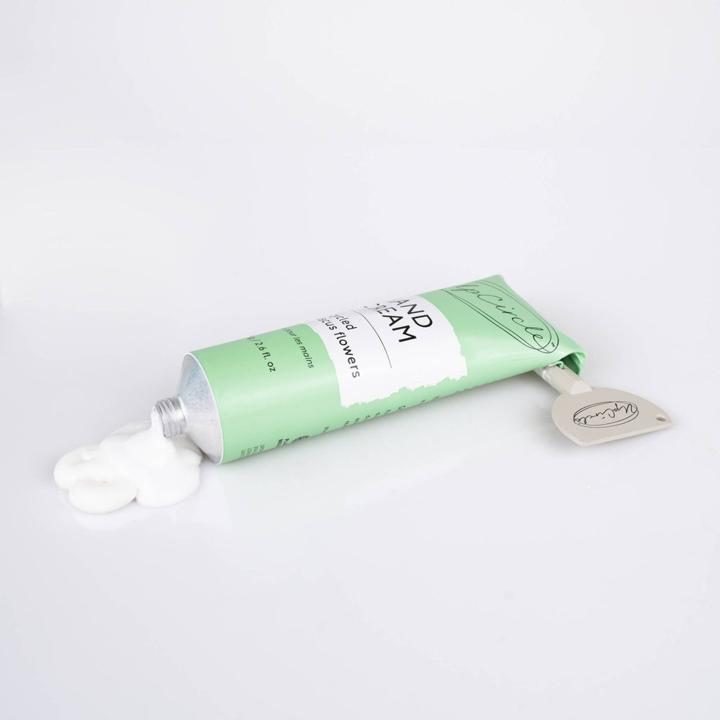 Green tube of UpCircle Hand Cream on a white background. White cream has been squeezed from the tube and a grey tube squeezer is at the top of the tube.