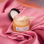 Jar of UpCircle lip balm with a spoon on pink fabric